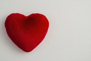 red plush heart pillow resting on clean white background its texture illuminated with soft highlights