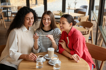 Woman taking picture of coffee drinks during meeting with her friends in cafe
