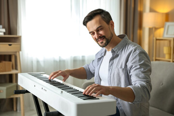 Fototapeta premium Man playing synthesizer at home. Electronic musical instrument
