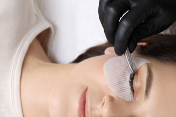 Woman undergoing lash extensions procedure in beauty salon, top view