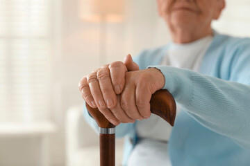 Lonely senior woman with walking cane indoors, closeup. Space for text