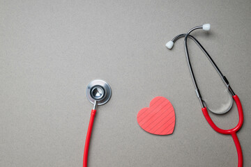 Stetascope and heart shaped note pad on gray background. Heart disease awareness background.