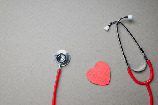 Stetascope and heart shaped note pad on gray background.  Heart disease awareness background.