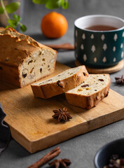 Spicy pie with fruits, nuts and spices on a wooden board, on a dark background