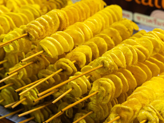 Spiral potatoes fried on a stick on a tray at a night market. Asian street food Thailand.