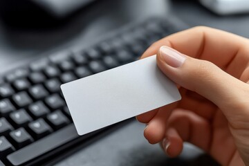 A hand holds a blank card near a keyboard, suggesting a potential identification or access use.