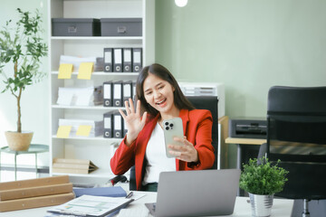 An Asian businesswoman works at her desk in a modern office, smiling while using a tablet to review financial analysis reports, manage accounting tasks, and oversee banking and loan documentation