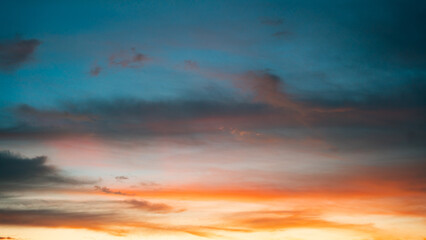 Elegant sunset sky transitioning from deep blue to glowing orange with delicate pink and gray cloud details