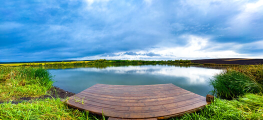 panorama with wooden pontoon overlooking the lake at sunset