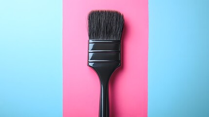 Paint brush with black bristles paints a line between pink and light blue backgrounds, showcasing a minimalist composition and creative transition in flat lay photography.