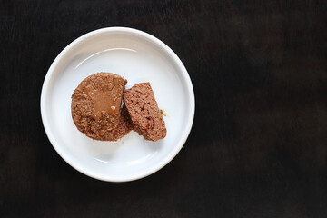 Cat food, pate, top view. Canned food for pets in a round white plate on a dark background. Tasty and healthy food for domestic cats. A portion of wet food, soft pate for a cat on a plate. Copy space