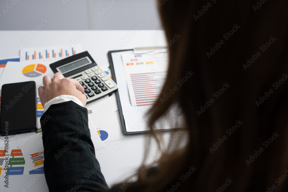 Poster a dedicated business professional is diligently using a calculator at their desk while examining a m