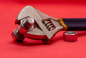 Bolts and nuts with a tool on a red background