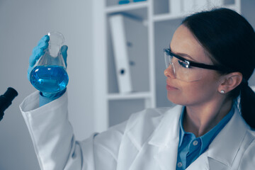 In a wellorganized lab, a dedicated scientist analyzes a vibrant blue solution, highlighting the importance of precision, detail, and rigorous investigation in biochemistry research