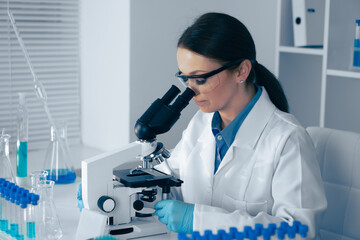 In a modern lab, a skilled female scientist analyzes biological and chemical samples under a...