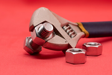 Bolts and nuts with a tool on a red background