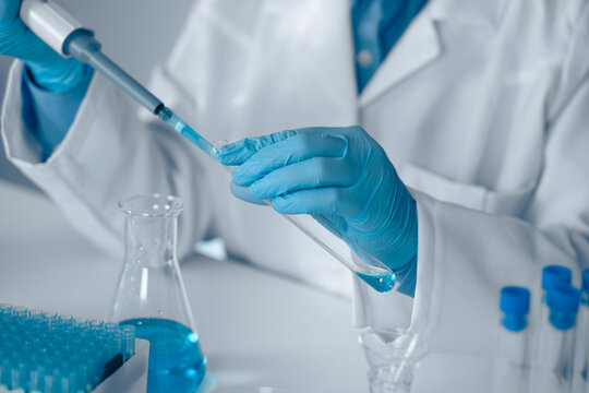 A Laboratory Technician is currently engaged in conducting a detailed experiment using a pipette within a modern laboratory environment, illustrating key themes in scientific research and safety