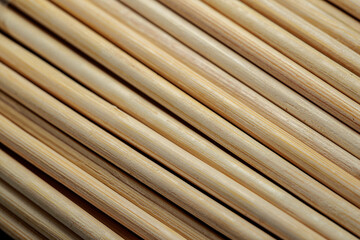 Close-up of numerous light brown, slender sticks arranged in parallel diagonal lines, creating a textured pattern.
