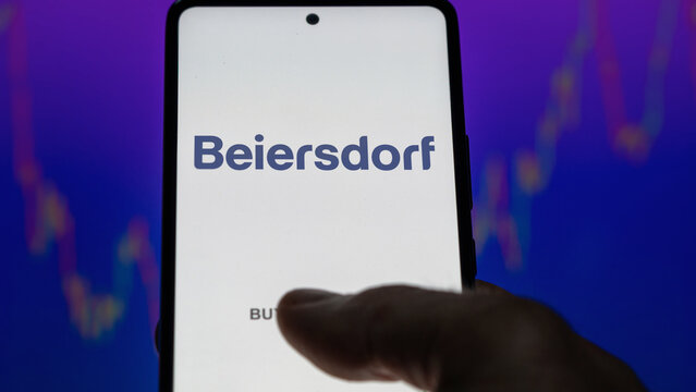 An investor analyzing the beiersdorf etf fund on a screen. A phone shows the prices of Beiersdorf