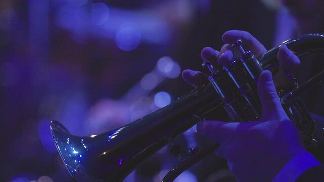 A musician playing a solo on a flugelhorn which is a brass instrument during a live jazz performance in dim lighting conditions. Nr.2
