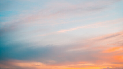 Dynamic sunset scene showcasing streaks of orange and pink clouds against a fading blue sky.
