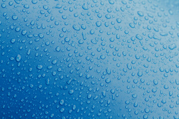 Water droplets on top a textured blue surface.
