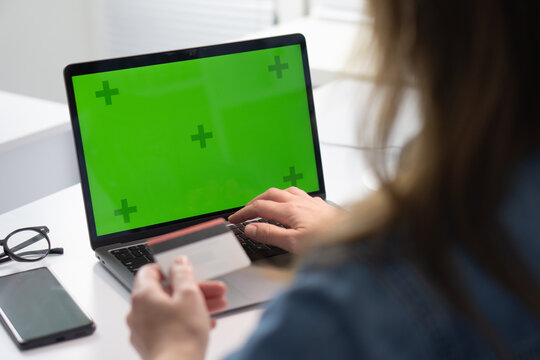 A person is actively using a laptop that has a green screen background, which is intended for display or mockup purposes during their work session, emphasizing a modern and productive workspace setup
