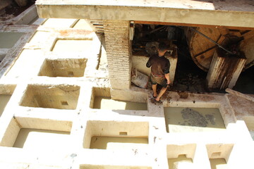 Ouvrier dans une usine de fabrication artisanale du cuir avec des peaux de mouton et de chèvre au Maroc à Fes