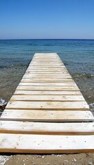 Fototapeta premium Wooden Boardwalk Leading to Calm, Blue Ocean on a Sandy Beach, Summer Vacation Concept