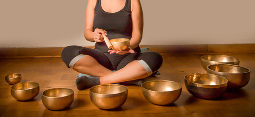 A woman using Tibetan singing bowls for sound healing, meditation, and relaxation. Ideal for...