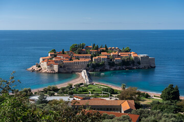 most popular place in Montenegro - Saint Stefan (Sveti Stefan) island. Orthodox church, beach, turquoise sea, view point, scenic path, green park. Cloudless sky © marekfromrzeszow
