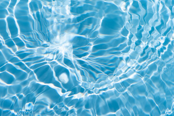 Blue water with ripples on the surface. Defocus blurred transparent blue colored clear calm water surface texture with splashes and bubbles. Water waves with shining pattern texture background.