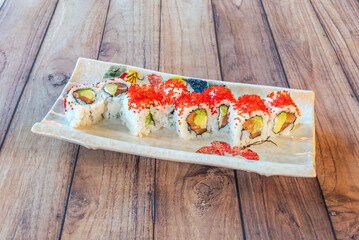 A sheet of nori seaweed is placed on a bamboo mat and an even layer of rice is spread, leaving a free edge on top