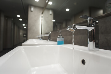 many white basin sinks with a mirror for washing hands and face in a public restroom