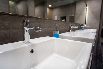 many white basin sinks with a mirror for washing hands and face in a public restroom