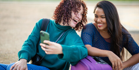 Two friends taking a selfie while sitting with suitcase