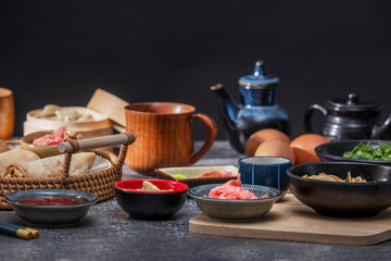 Various bowls with condiments and sauces on a grey stone table