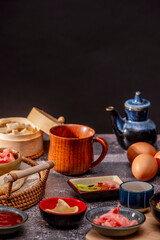 Various bowls with condiments, jars, wooden cups and sauces on a gray stone table