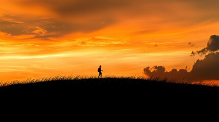 Silhouette of a Solo Walker on a Hill at Sunset with Dramatic Orange and Yellow Sky Surrounded by Clouds and Grassy Terrain