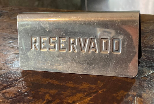 Metal reserved reservado sign on old wooden table in a spanish restaurant. 