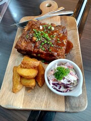 Barbecued ribs with vegetables on cutting board, High angle view of roasted ribs with coleslaw and fries served in plate on table