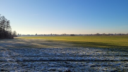 The skyline of the village of Wolfschlugen, Germany behind fields that are partly frozen.