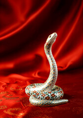 lunar new year celebration.  Elegant ceramic snake figurine on luxurious red silk background