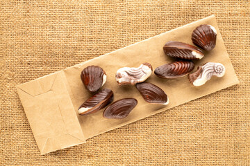 Several chocolate candies with ceramic dishes on jute cloth, close-up, top view.