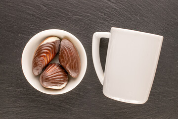 Several chocolate candies with ceramic dishes on slate stone, close-up, top view.
