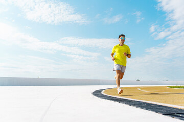 Individual runs along a curved pathway under a bright blue sky in a sunny outdoor setting