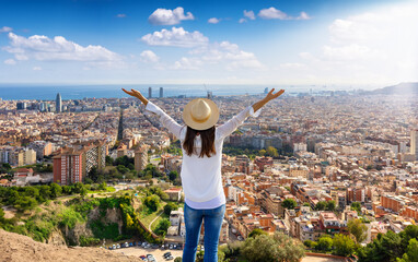 A happy tourist woman enjoys the panoramic view of the skyline of Barcelona, Spain, during a sunny day