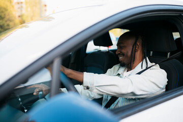 Cheerful man driving modern electric car in city