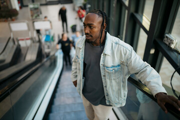 Stylish man going up on escalator in shopping mall