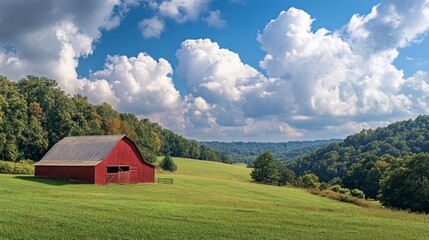 Obraz premium A striking red barn stands peacefully in a sprawling green field surrounded by trees and rolling hills. Fluffy white clouds drift across the clear blue sky, creating a serene atmosphere